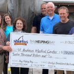 Check presentation to St. Andrews Community Medial Center from a Bay Helping Bay event